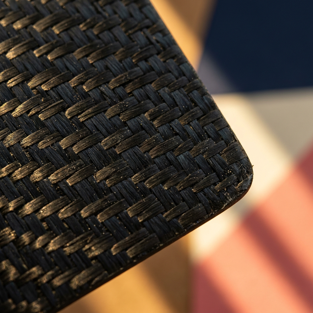 Macro of a raw woven carbon fibre paddle surface showing the twill weave and its fine grit texture