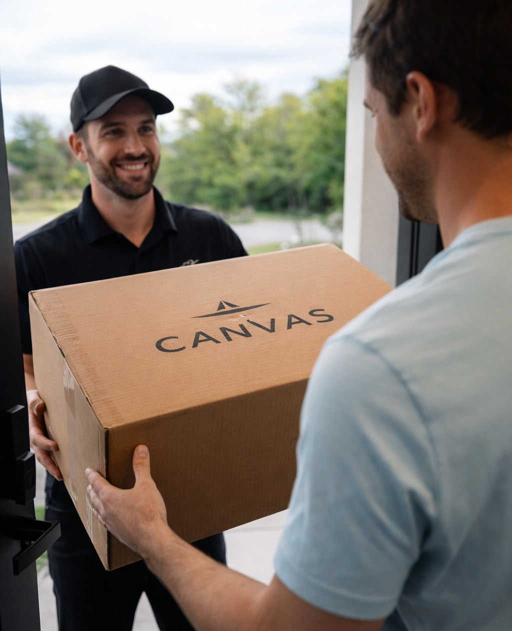 Man receiving a pickleball delivery box from a delivery person with 'Canvas' branding.
