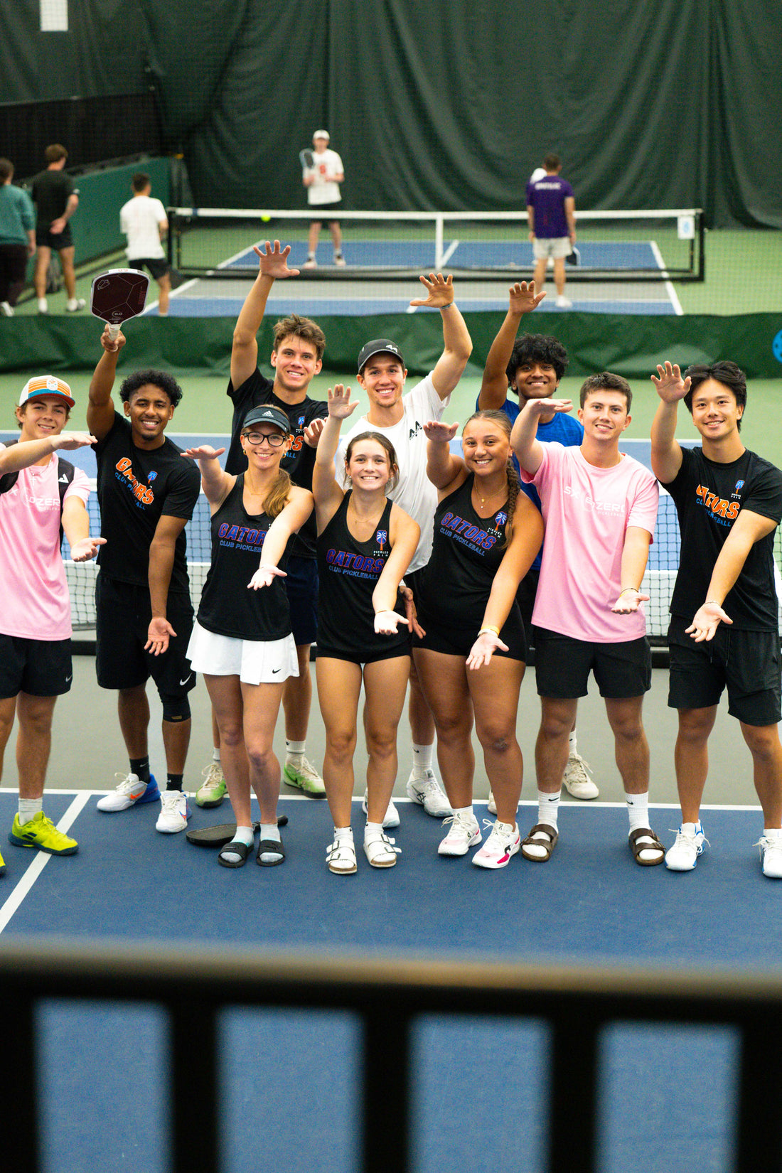 Group of pickleball players posing on a pickleball court with their custom pickleball gear