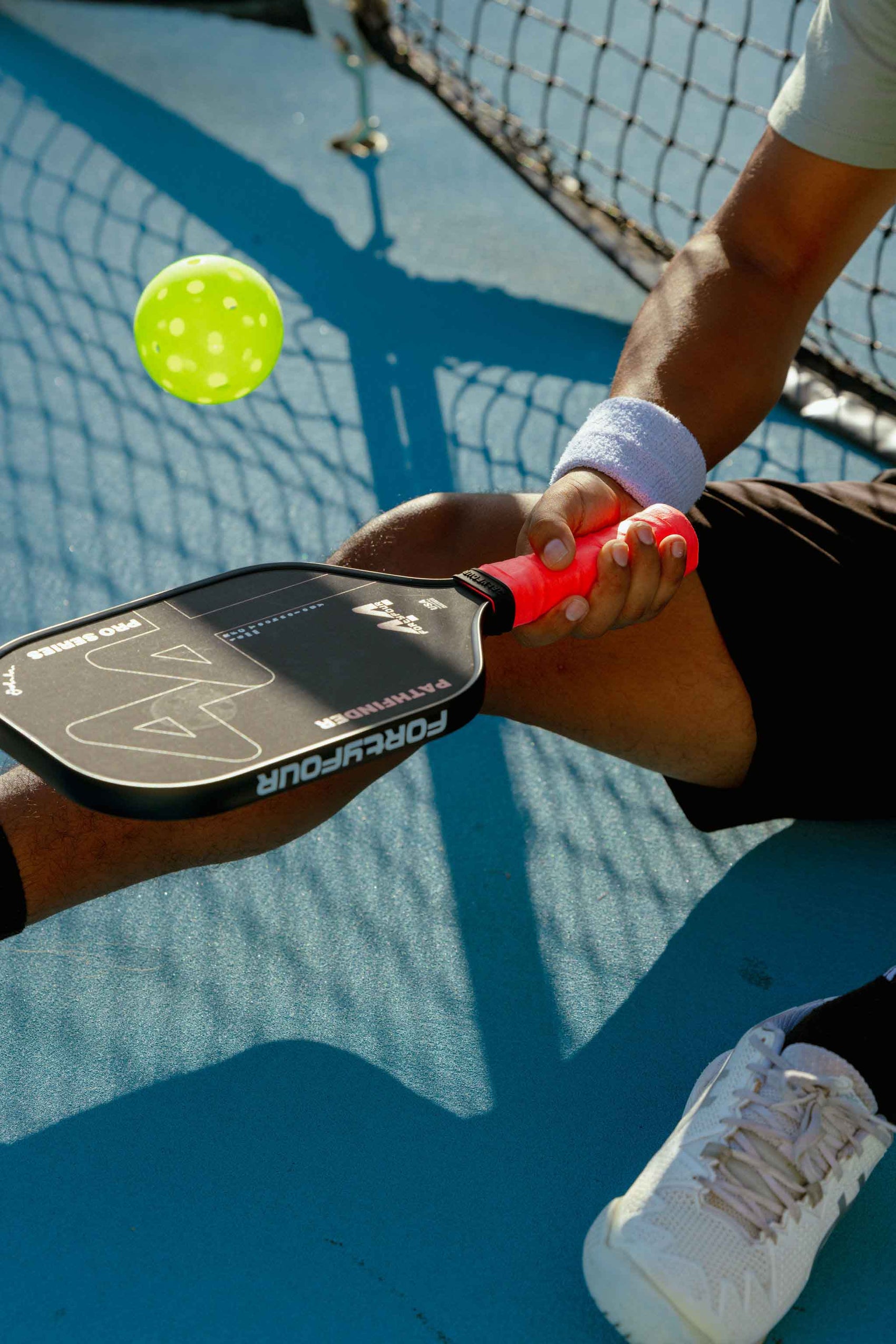 Person holding a pickleball paddle and ball on a court
