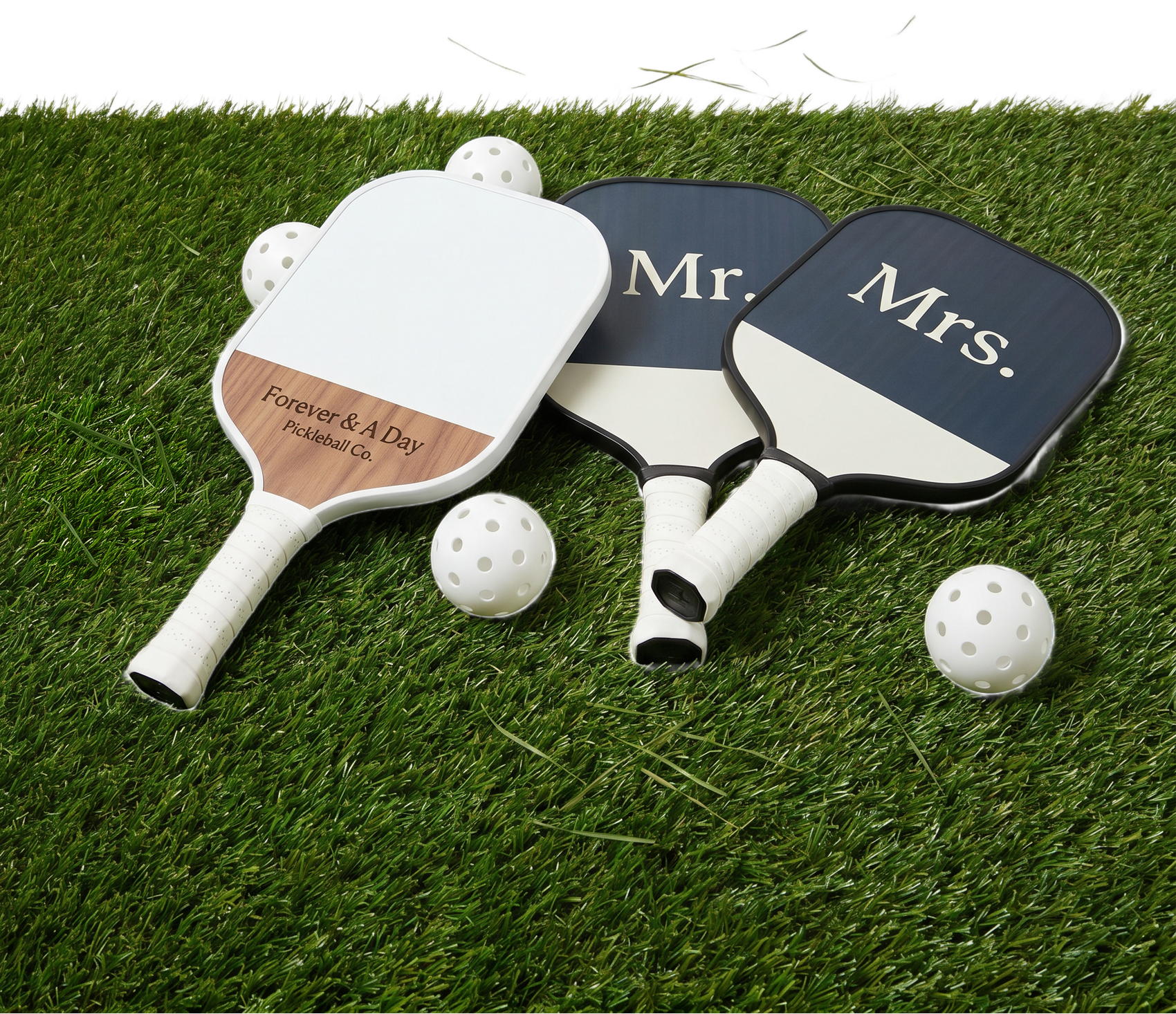 Two custom wedding pickleball paddles labeled 'Mr.' and 'Mrs.' with two balls on a grass surface.