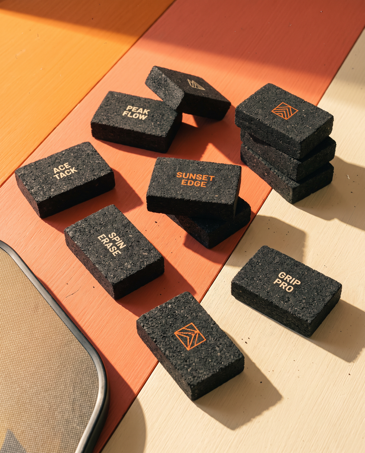 Custom paddle erasers laid out on a warm colour-blocked surface, each printed with a different logo