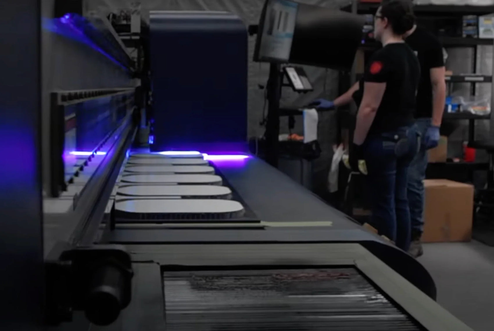 Person working with a large printing machine in a canvas pickleball facility